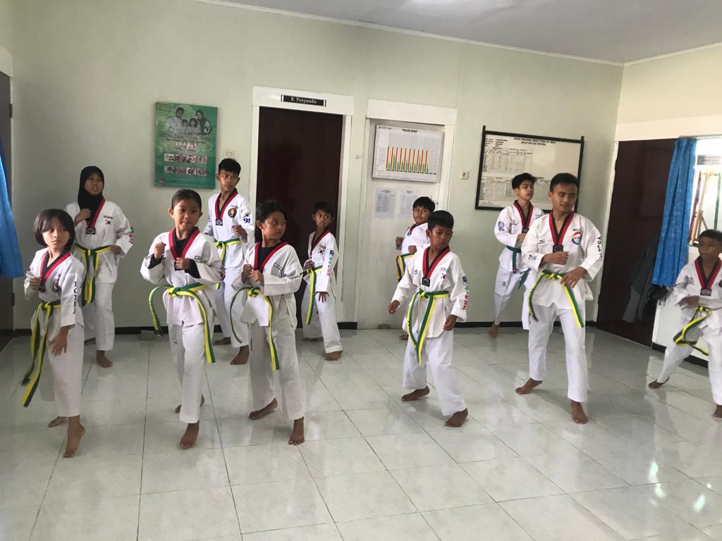 Peserta kelas taekwondo berlatih gerakan dasar di dalam ruangan